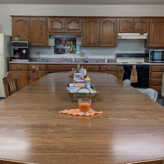 A spacious kitchen featuring a long wooden dining table and classic cabinetry.