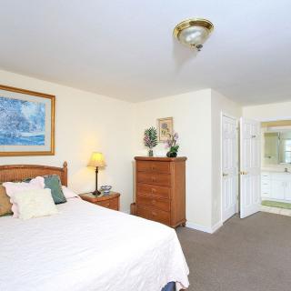 A cozy bedroom with a bed, dresser, and a view into the bathroom.