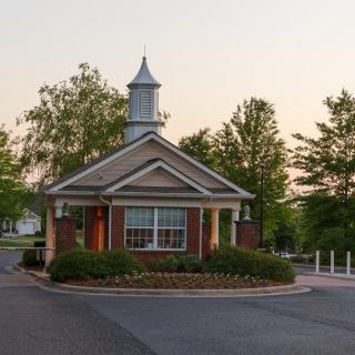 A small building with a cupola surrounded by trees and landscaping.