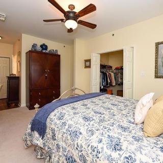 A cozy bedroom featuring a floral bedspread, ceiling fan, and an open closet.