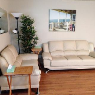 A modern living room with beige sofas, a tall lamp, and a houseplant.