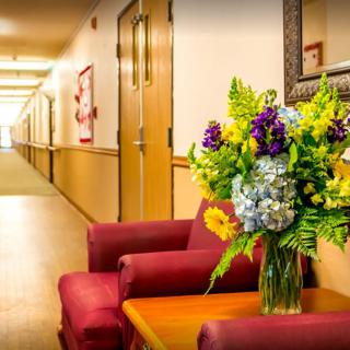 A cozy hallway with a vibrant bouquet of flowers on a table between two red chairs.