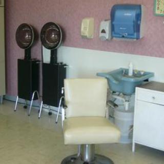 An empty hair salon with a styling chair, hair dryers, and a washing sink.