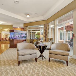 A cozy living room with two armchairs and a small table, featuring large windows and elegant decor.