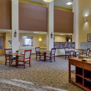 Spacious dining area with multiple tables and chairs in a well-lit, carpeted room.