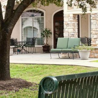 A peaceful outdoor patio area with chairs and benches surrounded by greenery.
