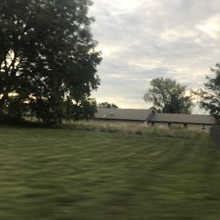 A serene view of a rural landscape with fields and trees under a cloudy sky.