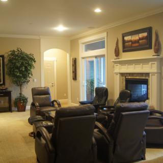 A cozy living room with comfortable armchairs arranged around a fireplace, featuring elegant decor and artwork.