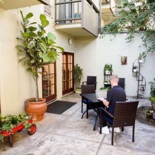A serene courtyard with outdoor seating, potted plants, and a person sitting at a table.