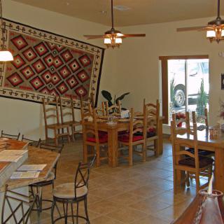 A cozy dining room with wooden furniture and a decorative tapestry on the wall.