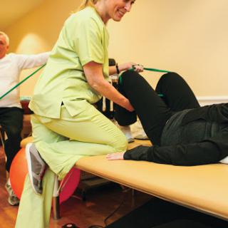 A physical therapist assisting a patient with rehabilitation exercises in a healthcare setting.
