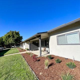 A single-story house with a well-maintained garden and a clear blue sky.