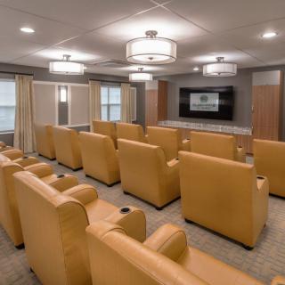 A cozy home theater with rows of comfortable recliner seating and a large projector screen.