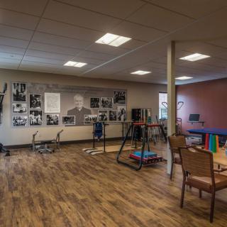 A spacious gym interior with exercise equipment, chairs, and photos decorating the walls.