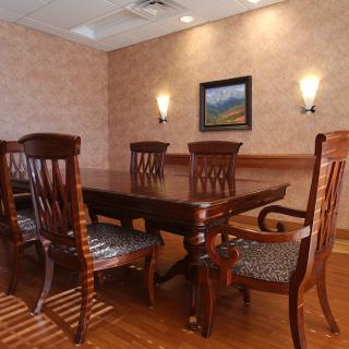 A well-lit conference room with a wooden table and chairs, adorned with wall sconces and a painting on the wall.