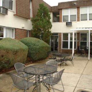 A patio area with metal tables and chairs in front of a brick building.