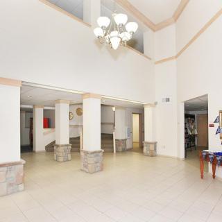 A spacious lobby with high ceilings, white columns, and a chandelier.