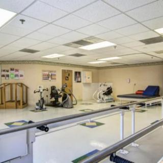 A physical therapy room equipped with various exercise machines and rehabilitation equipment.