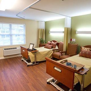 A modern hospital room with two patient beds and comfortable seating.