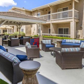 A cozy outdoor seating area in an apartment complex featuring comfortable patio furniture and a central gazebo.