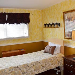 A cozy bedroom with yellow walls, a single bed, and decorative elements.