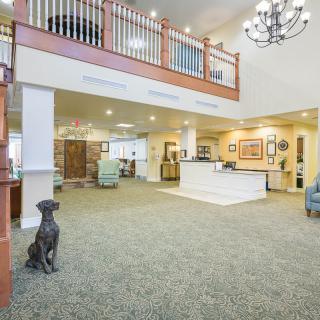 A modern lobby with a dog statue, chandelier, and reception desk in an open and inviting space.