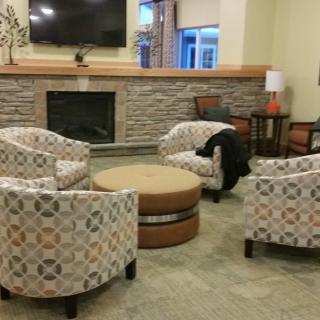 A cozy living room with a modern fireplace, patterned armchairs, and a round coffee table.