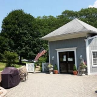 A small building with a large entrance, surrounded by trees and outdoor furniture, displaying an American flag.