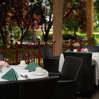 Outdoor restaurant seating with neatly set tables overlooking a garden view.