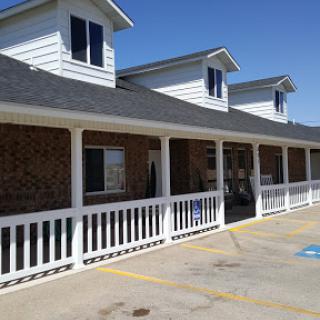 A charming building with a porch and multiple windows, showcasing a blend of brick and siding.