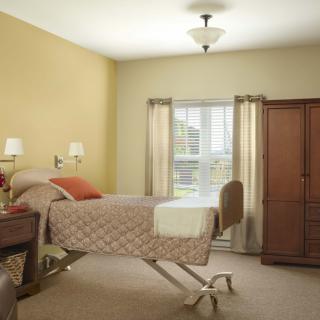 A cozy bedroom featuring a hospital bed, wooden cabinet, and soft lighting.