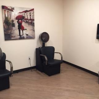 A cozy salon waiting area featuring stylish chairs and an artistic photograph.