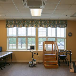 A rehabilitation therapy room featuring windows, stairs for practice, and exercise equipment.