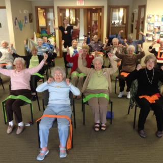 A group of seniors participating in a seated exercise class at a community center.