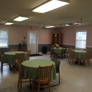 A community dining area with round tables and green tablecloths.