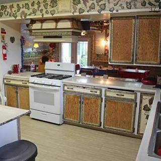 A vintage kitchen featuring wood cabinets, a white stove, and floral wallpaper.