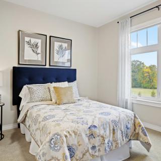A modern bedroom with a plush bed, decorative bedding, and framed artwork above the headboard.