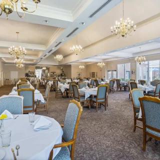 A spacious dining room with elegantly set tables and chandeliers.