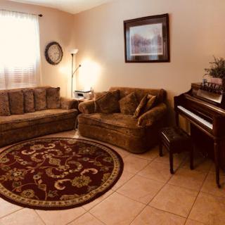 A cozy living room featuring comfortable seating, a piano, and decorative elements.