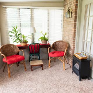 A cozy sunroom with wicker chairs, a small table and plants by the window.