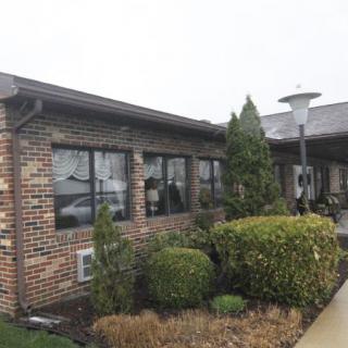 A brick building with neatly trimmed bushes and windows on a cloudy day.