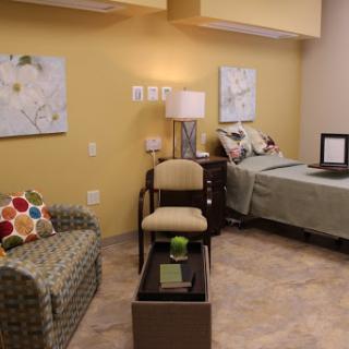 A cozy and inviting bedroom with a comfortable seating area, adorned with artwork and soft lighting.