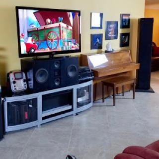 A cozy living room setup featuring a television, audio equipment, and a piano.