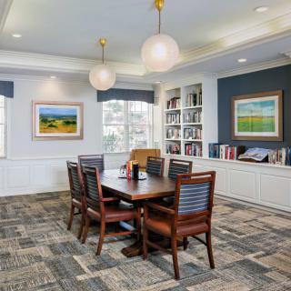 A well-decorated meeting room featuring a conference table, bookshelves, and framed artwork.