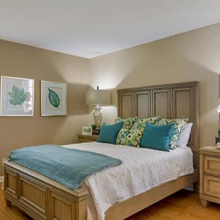 A cozy bedroom with a neatly made bed, decorative pillows, and warm lighting.