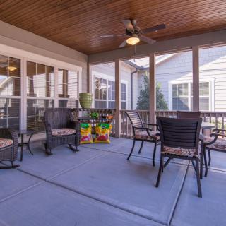 A cozy screened porch with outdoor seating and a ceiling fan.