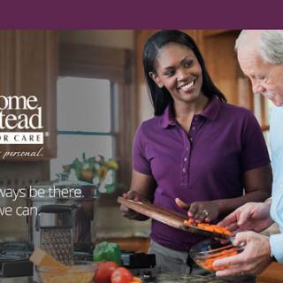 A caregiver assists an elderly man with food preparation in the kitchen.
