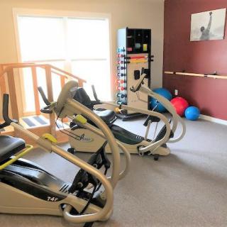 A well-lit gym with cardio machines and exercise equipment.
