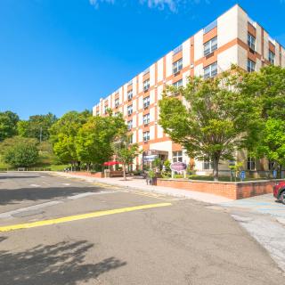 A sunny day view of a residential apartment building surrounded by trees.