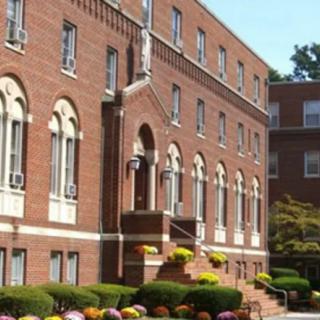 A brick building with arched windows and well-maintained landscaping.